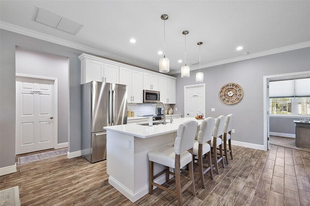 kitchen featuring sink, appliances with stainless steel finishes, a kitchen island with sink, white cabinets, and hardwood / wood-style flooring