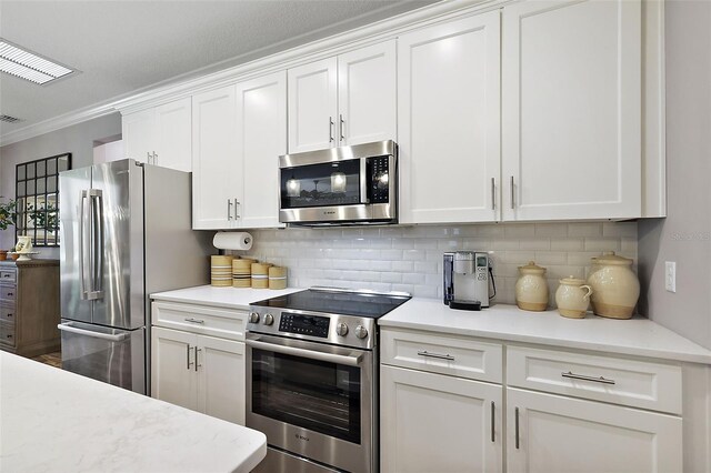 kitchen with white cabinets, stainless steel appliances, tasteful backsplash, and ornamental molding