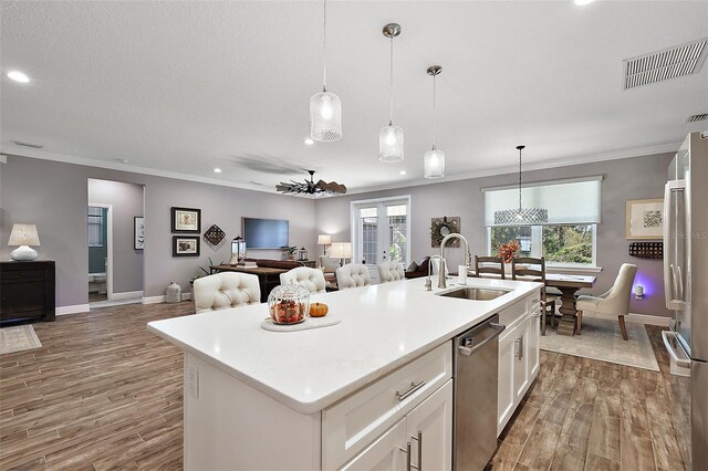 kitchen featuring white cabinetry, sink, stainless steel appliances, wood-type flooring, and a kitchen island with sink