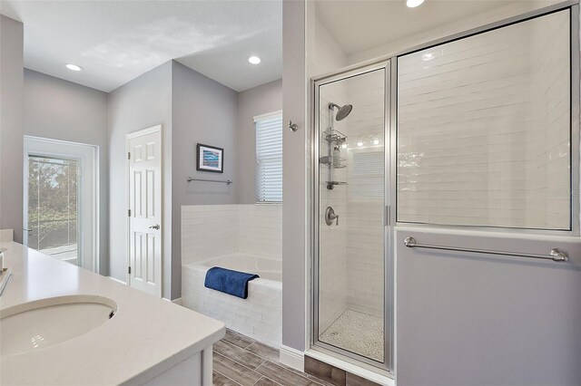 bathroom with hardwood / wood-style floors, vanity, and separate shower and tub