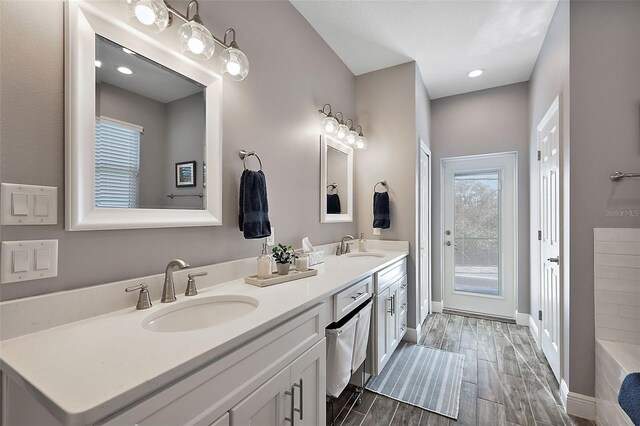 bathroom featuring hardwood / wood-style flooring, vanity, and a tub to relax in