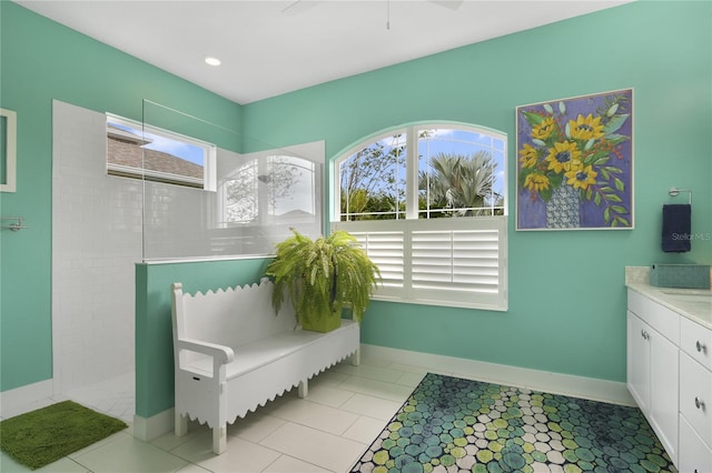 bathroom featuring tile patterned flooring, vanity, a healthy amount of sunlight, and tiled shower