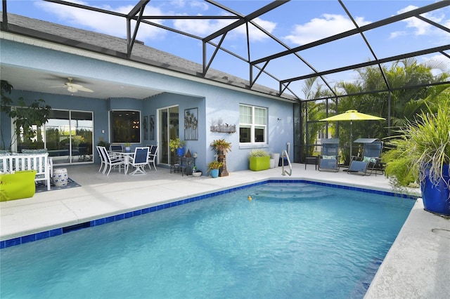 view of swimming pool with a patio, glass enclosure, and ceiling fan