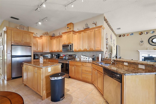 kitchen featuring dark stone counters, a kitchen island, stainless steel appliances, and a textured ceiling