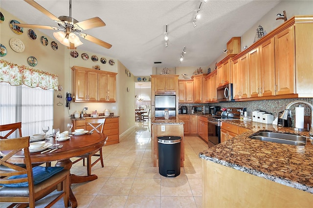 kitchen with sink, stainless steel appliances, dark stone counters, a textured ceiling, and decorative backsplash