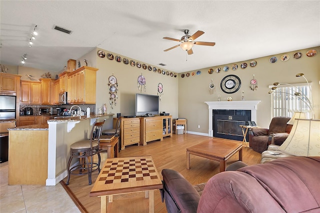 living room with a textured ceiling, light hardwood / wood-style floors, and ceiling fan