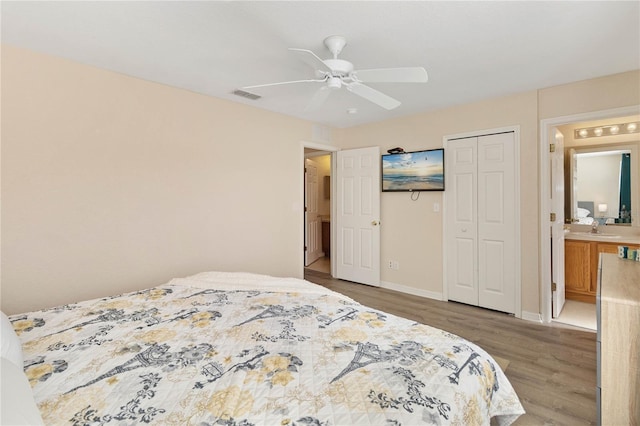 bedroom with ensuite bath, ceiling fan, sink, wood-type flooring, and a closet