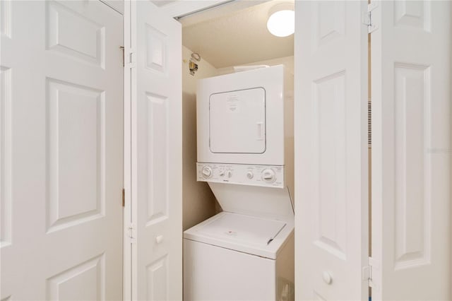 laundry room featuring a textured ceiling and stacked washer / dryer