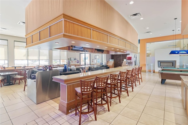 kitchen with light tile patterned flooring, a kitchen bar, a kitchen island, and pool table