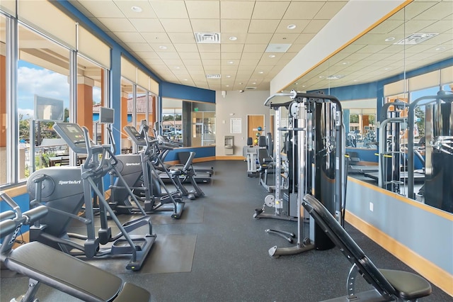 gym with a drop ceiling and a healthy amount of sunlight