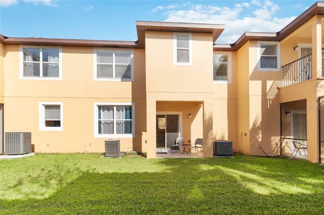 rear view of property featuring central air condition unit, a lawn, and a patio