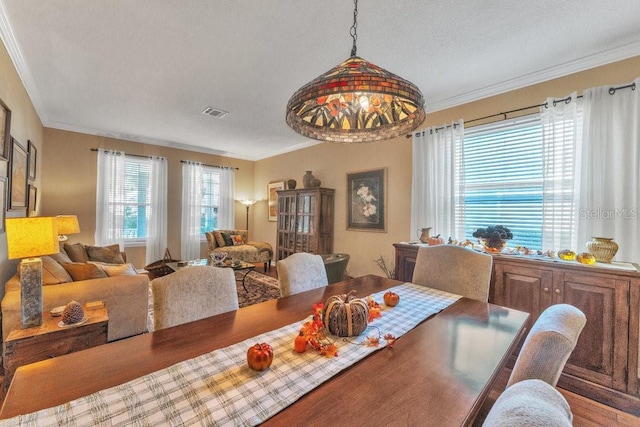 dining area with a textured ceiling, wood-type flooring, and crown molding