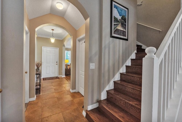 entrance foyer featuring ornamental molding, light tile patterned floors, and vaulted ceiling