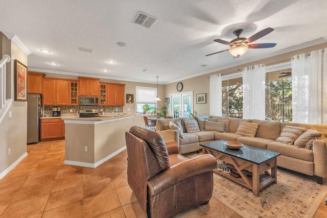 tiled living room with ceiling fan, a textured ceiling, and ornamental molding