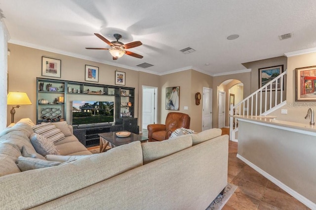 tiled living room with a textured ceiling, ceiling fan, and crown molding