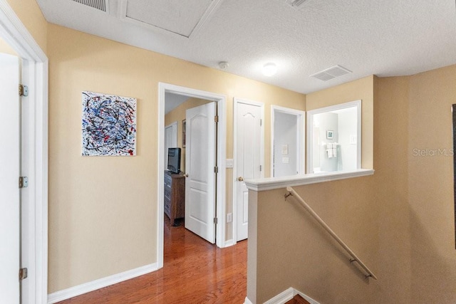 hallway with hardwood / wood-style floors and a textured ceiling