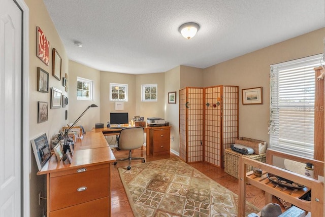 office area with light wood-type flooring and a textured ceiling