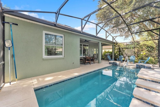 view of swimming pool featuring glass enclosure, ceiling fan, and a patio