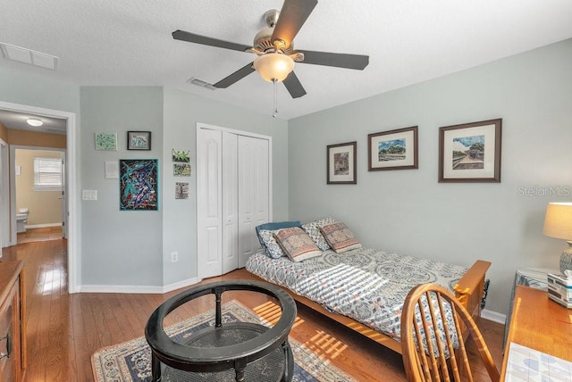 bedroom with a textured ceiling, ceiling fan, a closet, and dark hardwood / wood-style floors