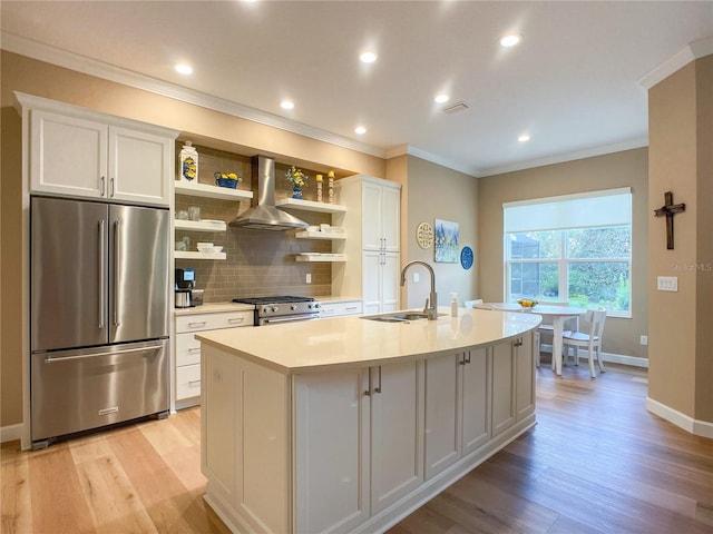 kitchen with white cabinets, high end appliances, wall chimney exhaust hood, and sink