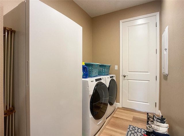 laundry area with separate washer and dryer and light hardwood / wood-style floors