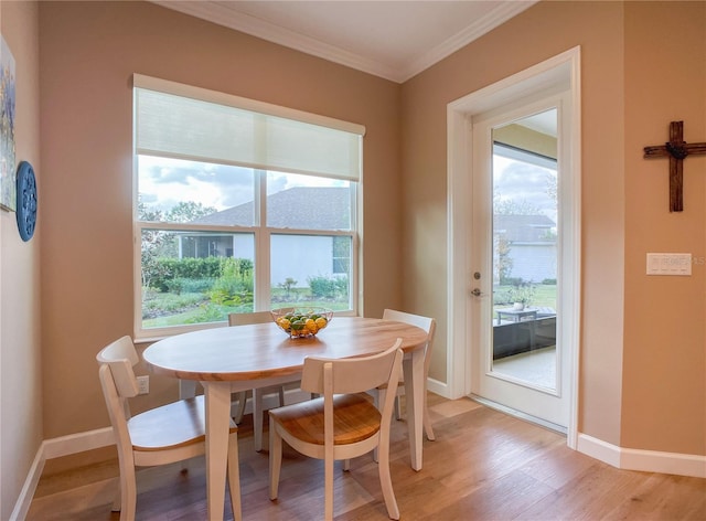 dining space featuring plenty of natural light, ornamental molding, and light hardwood / wood-style flooring