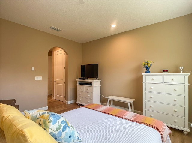 bedroom featuring a textured ceiling and light hardwood / wood-style floors