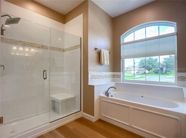 bathroom featuring plus walk in shower and hardwood / wood-style floors