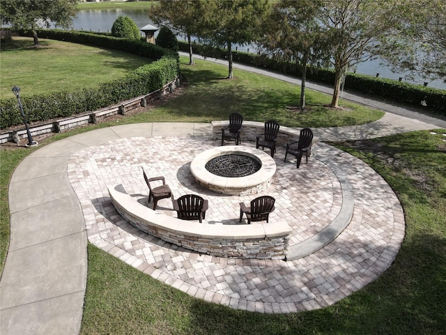 view of community featuring a water view, an outdoor fire pit, a patio area, and a lawn