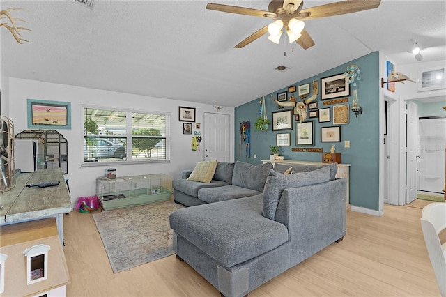 living room with a textured ceiling, ceiling fan, light hardwood / wood-style flooring, and vaulted ceiling