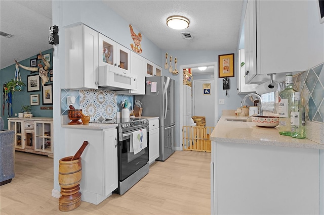 kitchen with white cabinets, appliances with stainless steel finishes, light hardwood / wood-style floors, and sink