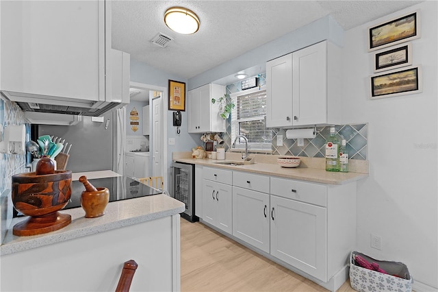 kitchen featuring light hardwood / wood-style flooring, white cabinetry, sink, wine cooler, and independent washer and dryer