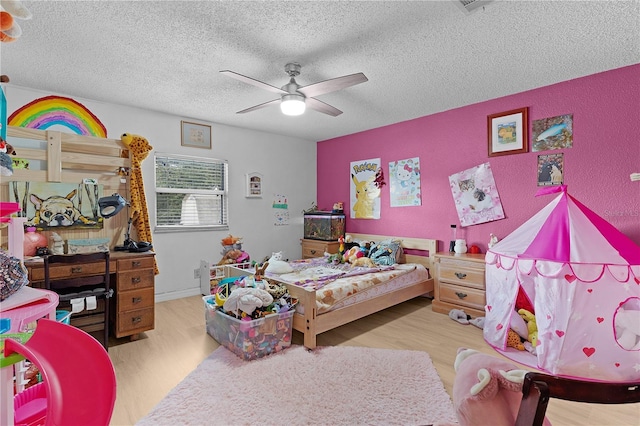 bedroom with ceiling fan, light hardwood / wood-style floors, and a textured ceiling