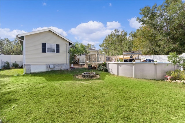 view of yard featuring a swimming pool side deck and an outdoor fire pit