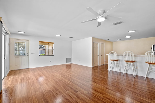 unfurnished living room featuring bar, dark hardwood / wood-style floors, and ceiling fan