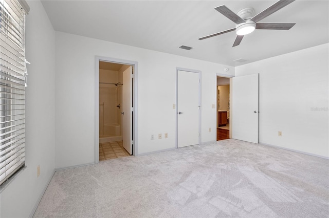 unfurnished bedroom with ensuite bath, light carpet, a closet, and ceiling fan