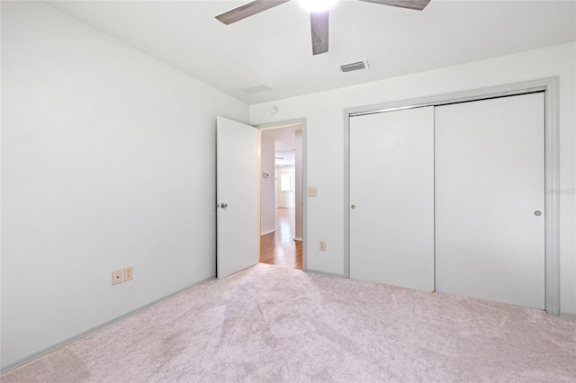 unfurnished bedroom featuring ceiling fan, a closet, and light carpet