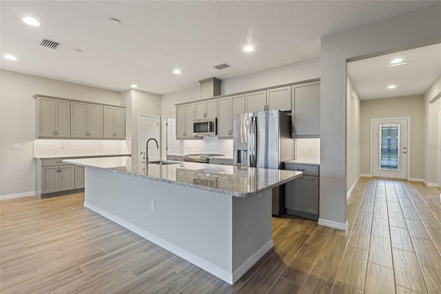 kitchen featuring gray cabinetry, a center island with sink, stainless steel appliances, and sink