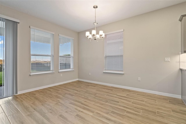 empty room with light hardwood / wood-style flooring and an inviting chandelier