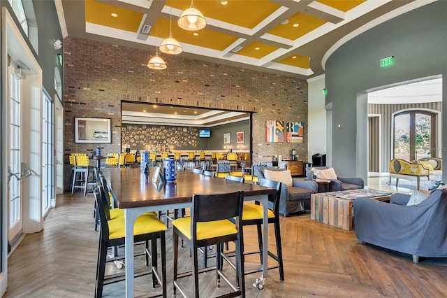 dining room with parquet floors, a towering ceiling, brick wall, and coffered ceiling