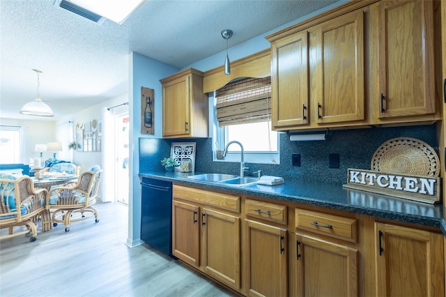 kitchen featuring dishwasher, sink, light hardwood / wood-style flooring, a textured ceiling, and decorative light fixtures