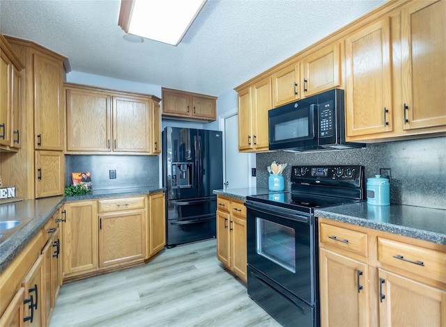 kitchen featuring tasteful backsplash, light hardwood / wood-style flooring, black appliances, and a textured ceiling