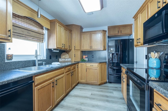 kitchen featuring backsplash, a textured ceiling, sink, black appliances, and light hardwood / wood-style flooring