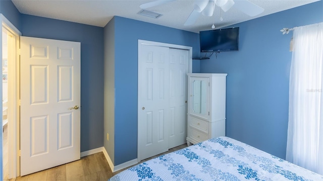 bedroom with ceiling fan, a closet, a textured ceiling, and light hardwood / wood-style flooring