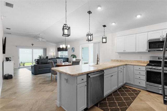 kitchen featuring kitchen peninsula, appliances with stainless steel finishes, ceiling fan with notable chandelier, vaulted ceiling, and sink