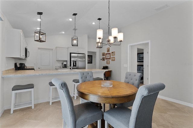 dining space with a chandelier, lofted ceiling, and light tile patterned flooring