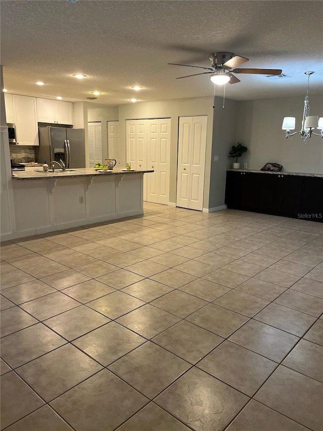 kitchen featuring a kitchen breakfast bar, white cabinetry, hanging light fixtures, kitchen peninsula, and stainless steel appliances