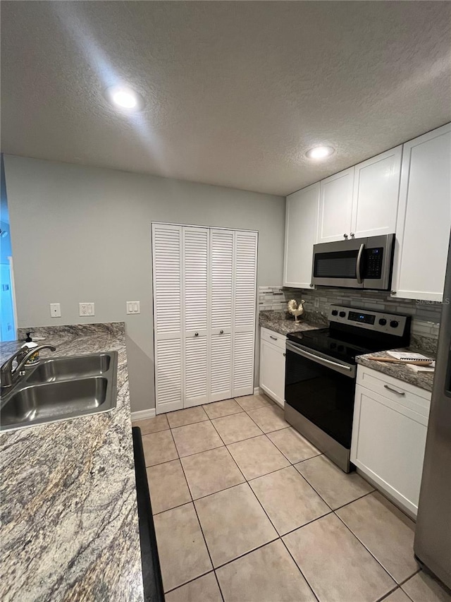 kitchen featuring decorative backsplash, stainless steel appliances, white cabinetry, and sink