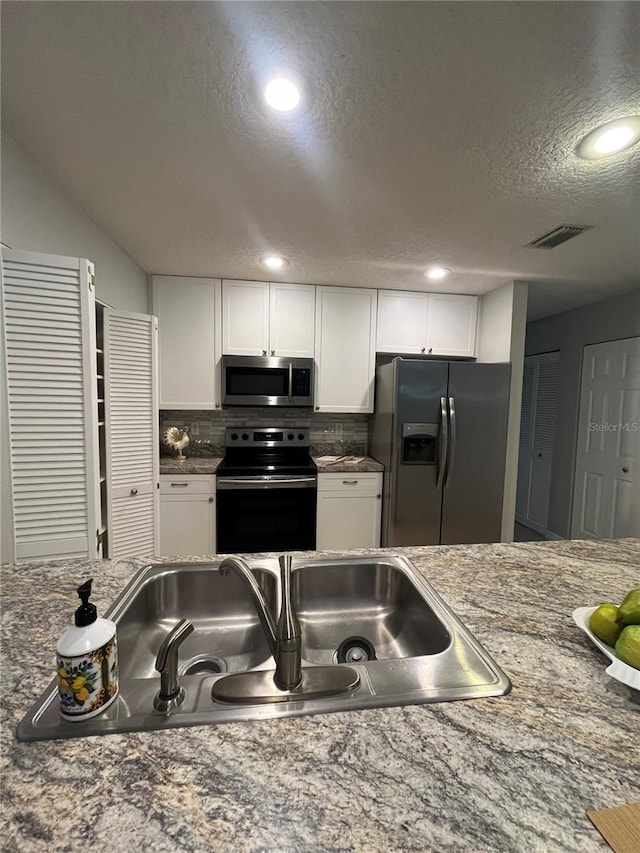 kitchen with white cabinetry, sink, decorative backsplash, appliances with stainless steel finishes, and a textured ceiling