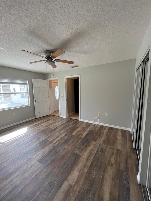 unfurnished bedroom featuring a textured ceiling, ceiling fan, and dark wood-type flooring